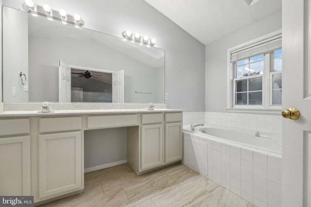 bathroom with a relaxing tiled tub, vanity, and vaulted ceiling