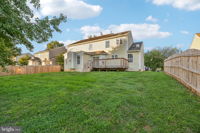 rear view of property featuring a wooden deck and a lawn