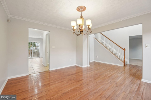 unfurnished room with an inviting chandelier, light hardwood / wood-style flooring, ornamental molding, and a textured ceiling