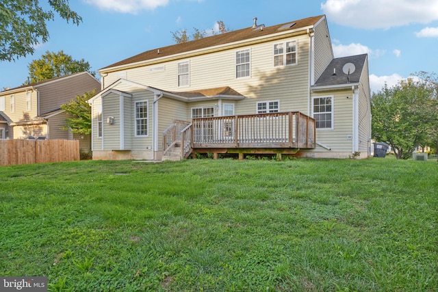 rear view of property featuring a wooden deck and a lawn