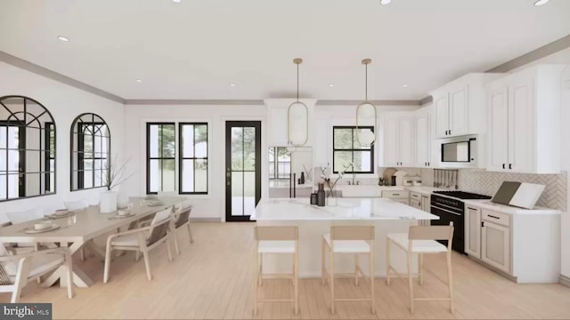 kitchen featuring decorative backsplash, a kitchen island, built in microwave, black gas stove, and white cabinetry