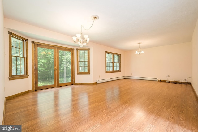 empty room with light wood-type flooring, french doors, a baseboard radiator, and a chandelier