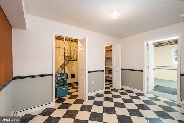 unfurnished bedroom featuring baseboard heating, a spacious closet, and a closet