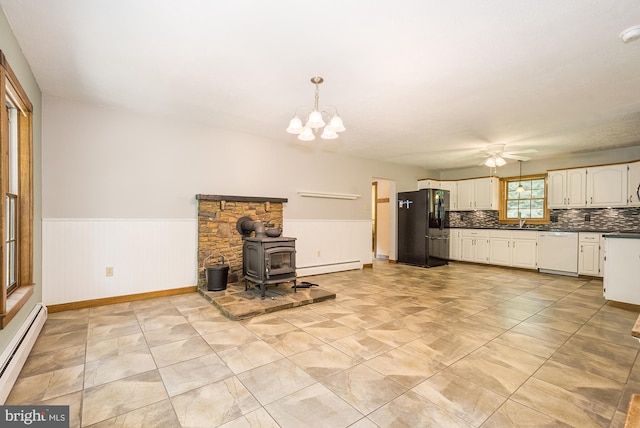 kitchen with white dishwasher, black fridge with ice dispenser, a wood stove, and baseboard heating