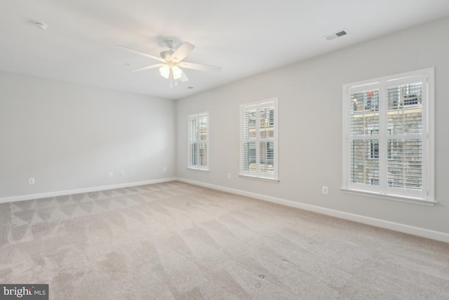 carpeted empty room with ceiling fan and plenty of natural light