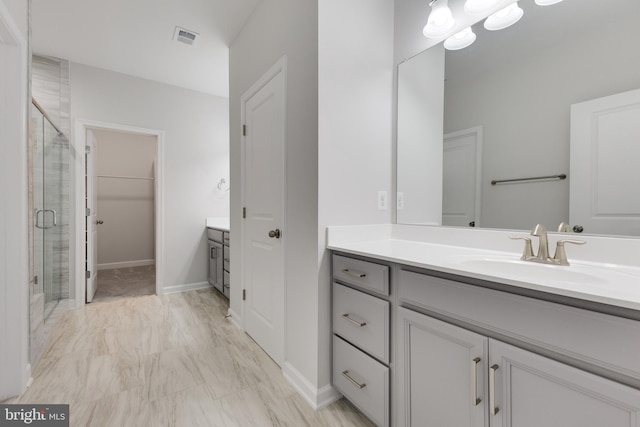 bathroom with a shower with shower door and vanity