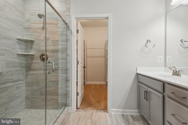 bathroom featuring a shower with shower door and vanity