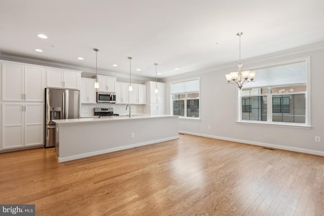 kitchen featuring stainless steel appliances, an island with sink, white cabinetry, and decorative light fixtures