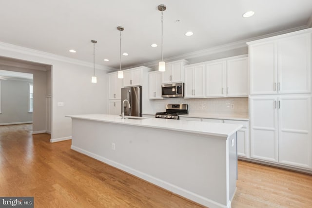 kitchen featuring a center island with sink, stainless steel appliances, light wood-type flooring, hanging light fixtures, and white cabinets