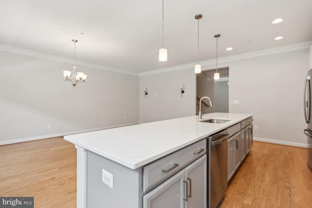 kitchen with hanging light fixtures, gray cabinetry, ornamental molding, and an island with sink