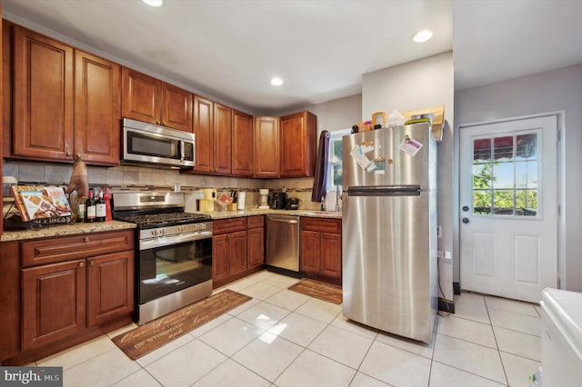 kitchen featuring light tile patterned floors, stainless steel appliances, and light stone counters