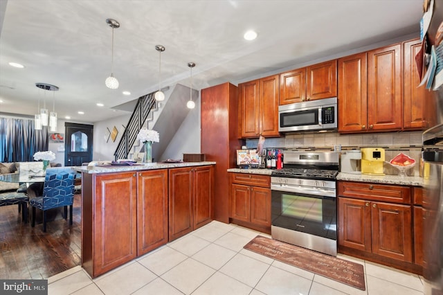 kitchen with kitchen peninsula, appliances with stainless steel finishes, backsplash, light stone countertops, and pendant lighting