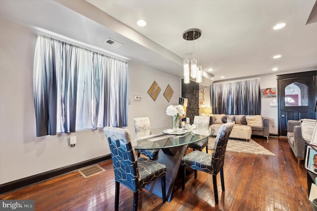 dining area with dark wood-type flooring and a notable chandelier