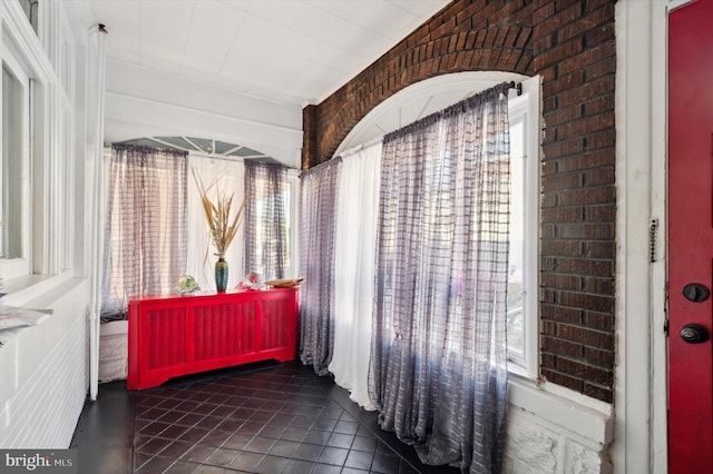 interior space with tile patterned flooring and brick wall