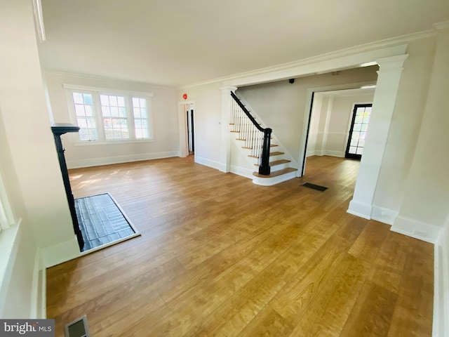 unfurnished living room with hardwood / wood-style flooring and crown molding