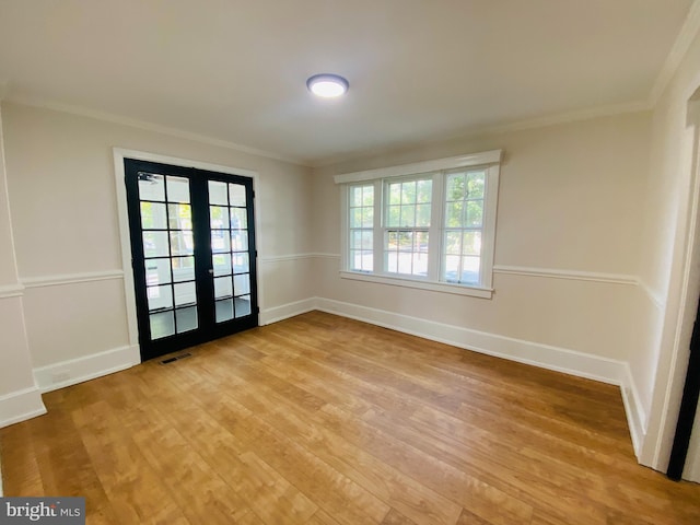 empty room featuring light wood-type flooring, ornamental molding, and french doors