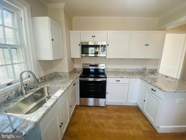 kitchen featuring sink, white cabinetry, ornamental molding, stainless steel appliances, and light hardwood / wood-style floors