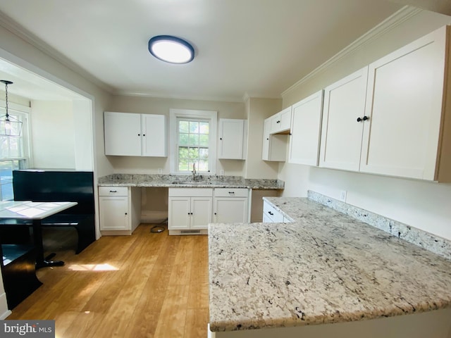 kitchen with white cabinetry, sink, light hardwood / wood-style floors, and ornamental molding