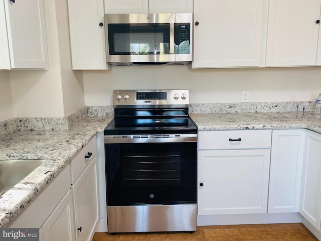 kitchen featuring white cabinetry, light stone countertops, and stainless steel appliances