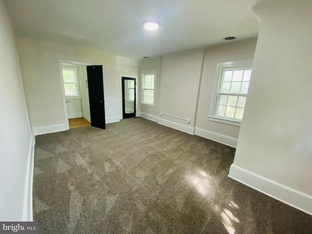 spare room featuring plenty of natural light and dark carpet