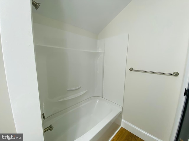 bathroom featuring hardwood / wood-style flooring, lofted ceiling, and shower / washtub combination