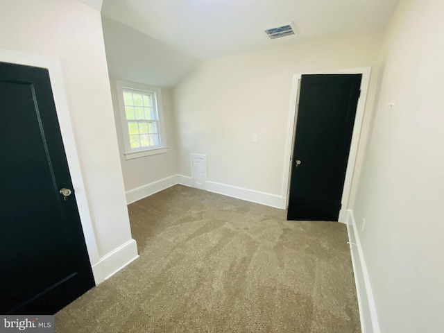 spare room featuring light colored carpet and vaulted ceiling