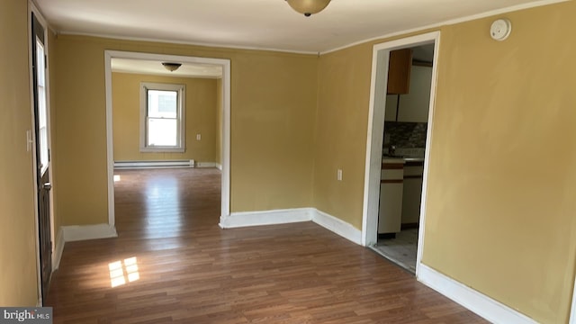 spare room featuring hardwood / wood-style flooring, crown molding, and a baseboard heating unit