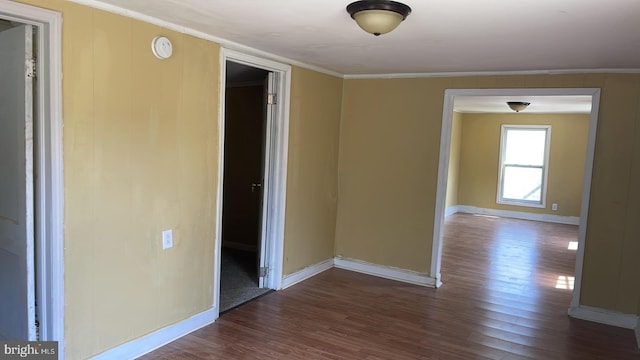 spare room featuring crown molding and dark wood-type flooring