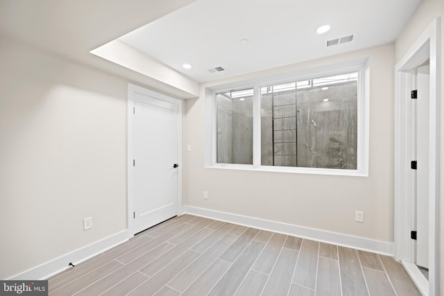 empty room featuring recessed lighting, baseboards, visible vents, and wood tiled floor