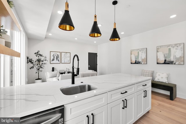 kitchen with dishwasher, white cabinets, sink, light hardwood / wood-style flooring, and light stone countertops