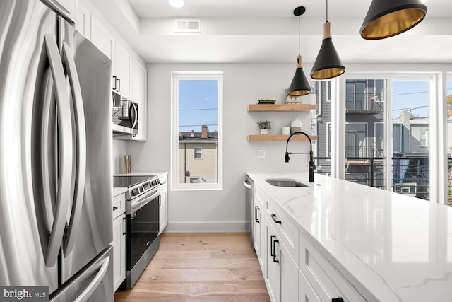 kitchen featuring light stone countertops, white cabinets, stainless steel appliances, and light hardwood / wood-style floors