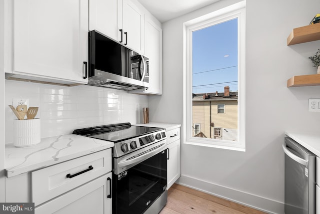 kitchen featuring white cabinetry, stainless steel appliances, light stone counters, and light hardwood / wood-style floors