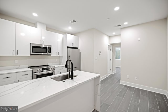 kitchen with sink, stainless steel appliances, white cabinetry, and light stone counters