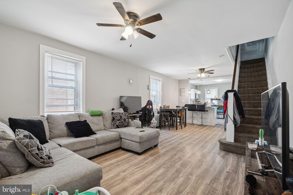 living room featuring light hardwood / wood-style flooring, ceiling fan, and a healthy amount of sunlight