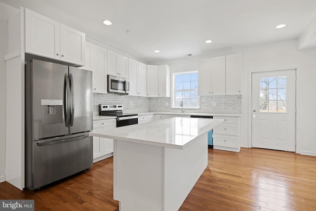 kitchen with white cabinets, stainless steel appliances, a kitchen island, and dark wood-type flooring