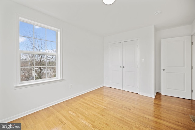 unfurnished bedroom with light hardwood / wood-style flooring and a closet