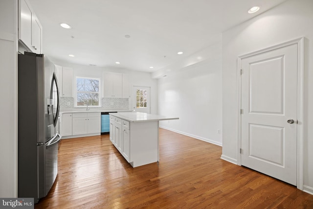 kitchen featuring tasteful backsplash, stainless steel appliances, hardwood / wood-style flooring, a center island, and white cabinetry