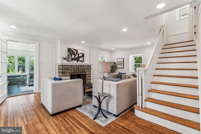 living room with a fireplace, crown molding, and wood-type flooring