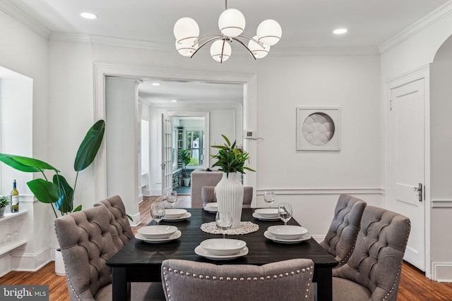 dining space featuring ornamental molding, wood-type flooring, and a chandelier