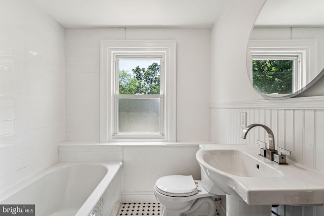 bathroom featuring sink, a bath, and toilet