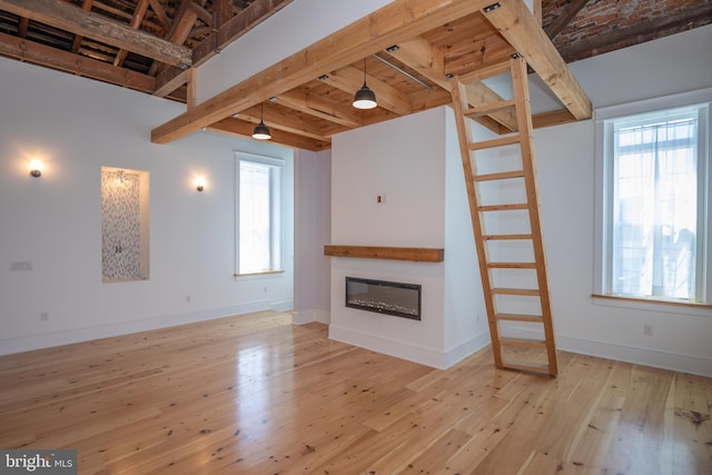 unfurnished living room featuring beamed ceiling and light hardwood / wood-style floors