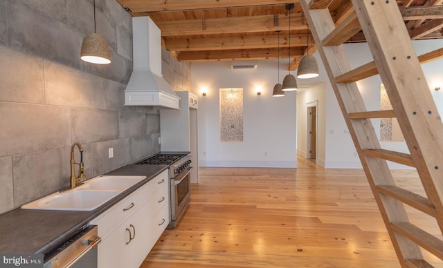 kitchen with pendant lighting, white cabinets, sink, beamed ceiling, and light hardwood / wood-style floors