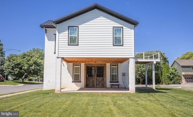 back of property with a yard, a balcony, and a patio