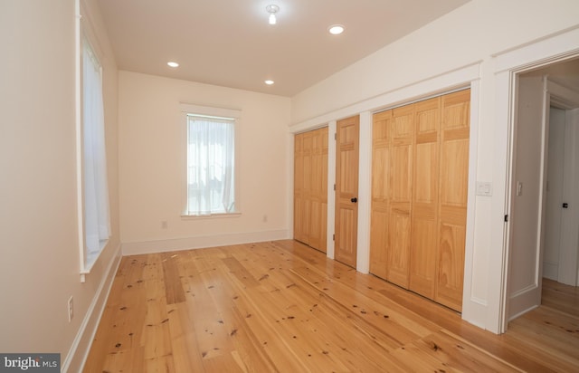 unfurnished bedroom with hardwood / wood-style flooring and two closets