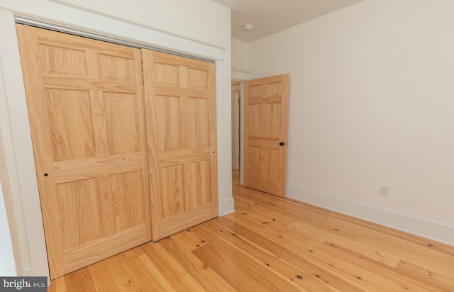 unfurnished bedroom with wood-type flooring and a closet