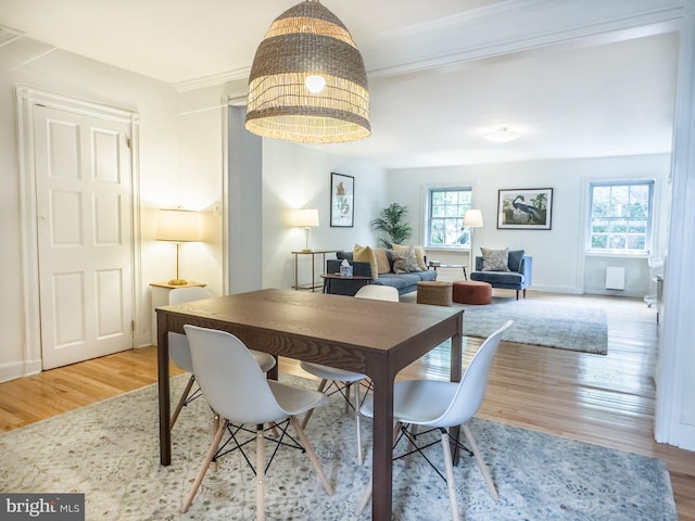 dining space with a healthy amount of sunlight, ornamental molding, and hardwood / wood-style flooring