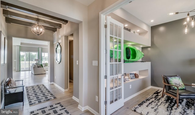 interior space featuring light hardwood / wood-style flooring, beamed ceiling, and a notable chandelier