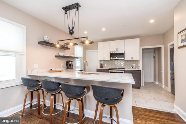 kitchen with hardwood / wood-style floors, a healthy amount of sunlight, appliances with stainless steel finishes, and pendant lighting