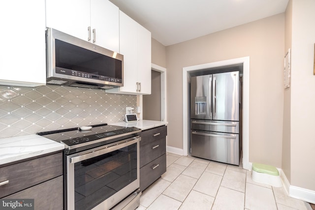 kitchen with white cabinets, light stone countertops, light tile patterned floors, tasteful backsplash, and stainless steel appliances