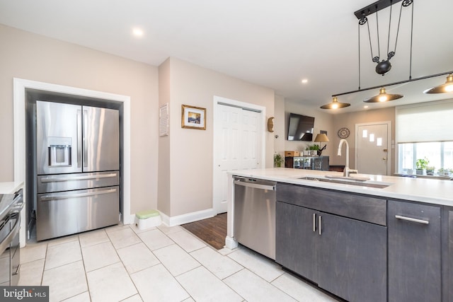 kitchen with light tile patterned floors, stainless steel appliances, hanging light fixtures, and sink